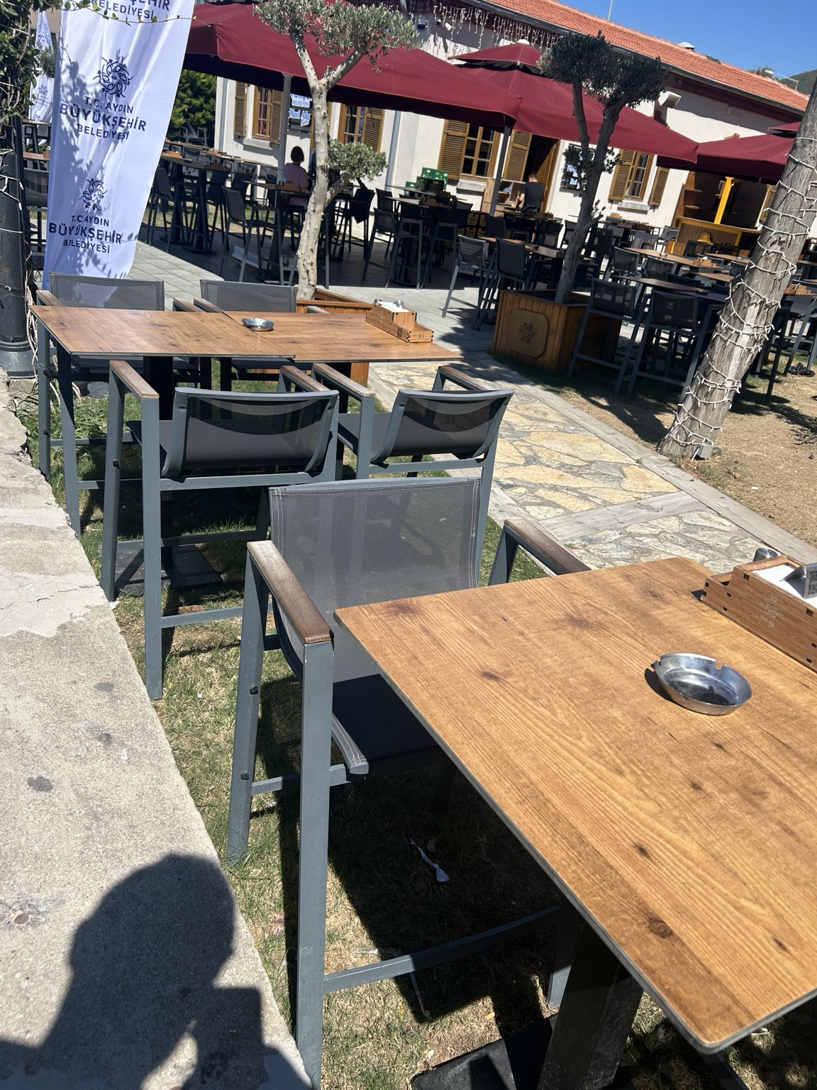 Kafe dış alanındaki ahşap görünümlü kompakt masa tablaları ve sandalyeler