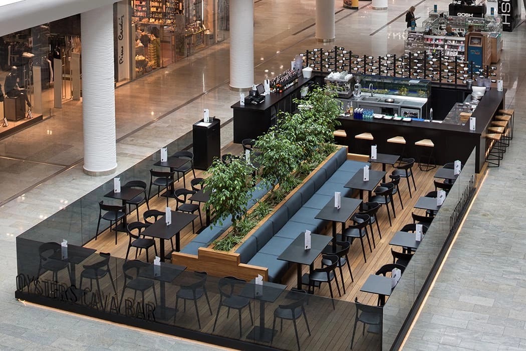 Kafe alanındaki siyah masa ve sandalye yerleşimi